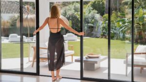 Vrouw opent schuifwand naar tuin met modern terras en veel lichtinval